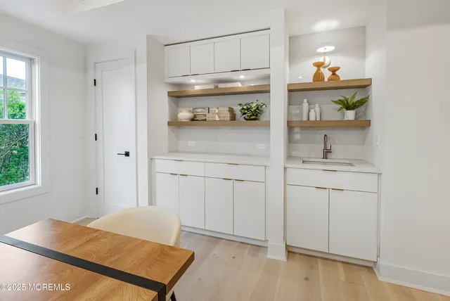 a kitchen with white cabinets and window