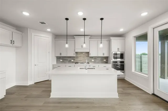 a view of a kitchen with kitchen island a sink stainless steel appliances and cabinets