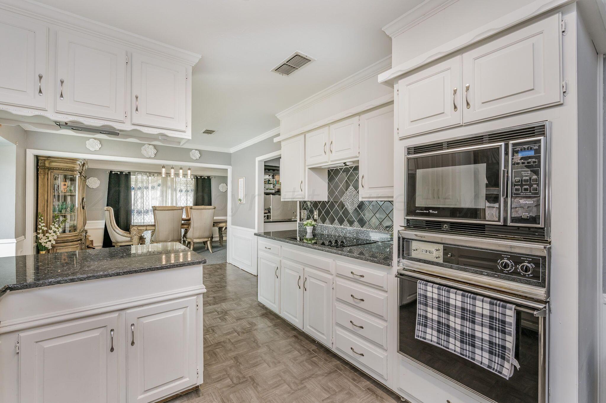 1109 Bennett Drive Dumas, TX 79029 - Photo 8 of 21 a kitchen with stainless steel appliances granite countertop a stove microwave and cabinets