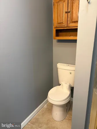 a white toilet sitting next to a wooden cabinet