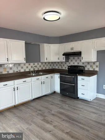 a kitchen with stainless steel appliances granite countertop a stove a sink and white cabinets