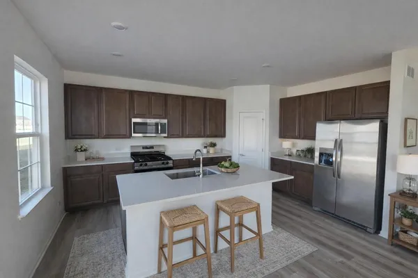 a kitchen with refrigerator a stove a sink and chairs
