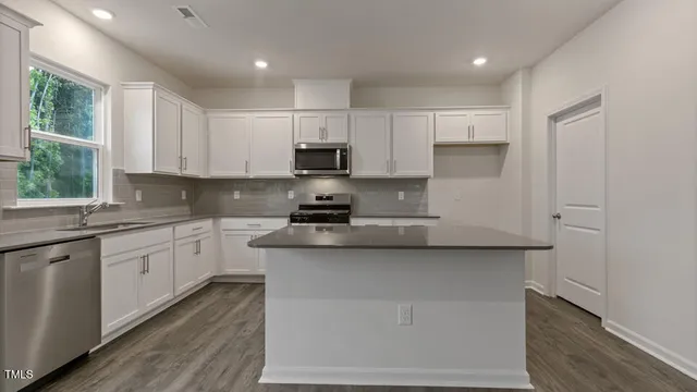 a kitchen with stainless steel appliances white cabinets a sink and a stove