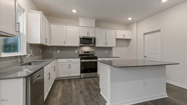 a kitchen with stainless steel appliances granite countertop white cabinets granite counter tops and a hard wood floors