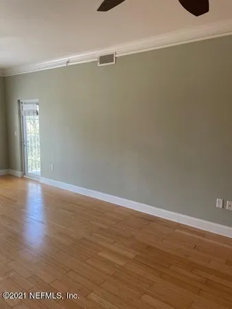an empty room with wooden floor and windows with curtains