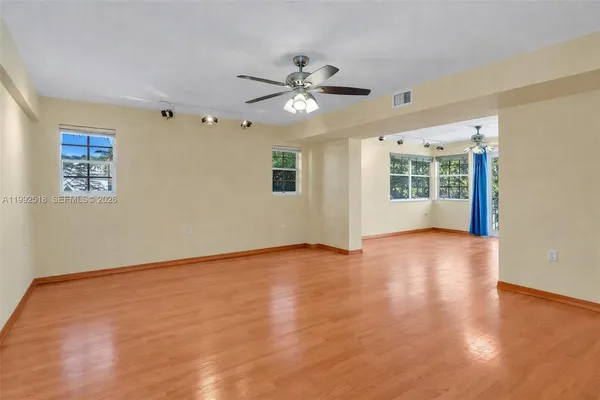a view of an empty room with a window and wooden floor