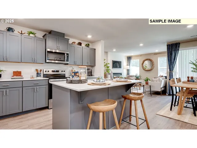 a kitchen with stainless steel appliances kitchen island a table chairs sink and cabinets