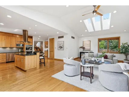 a kitchen with stainless steel appliances kitchen island granite countertop a refrigerator a stove a sink a dining table and chairs with wooden floor