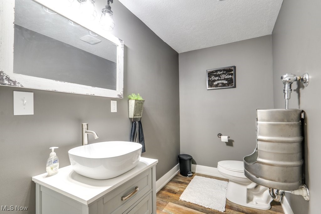 4121 New Milford Road Rootstown, OH 44272 - Photo 46 of 50 Half bathroom with baseboards, toilet, a textured ceiling, vanity, and wood finished floors