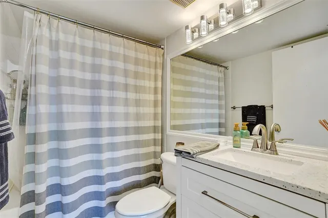 a bathroom with a granite countertop sink a toilet and shower