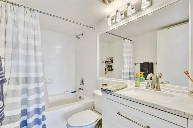 a bathroom with a granite countertop sink a toilet a mirror a bathtub and shower