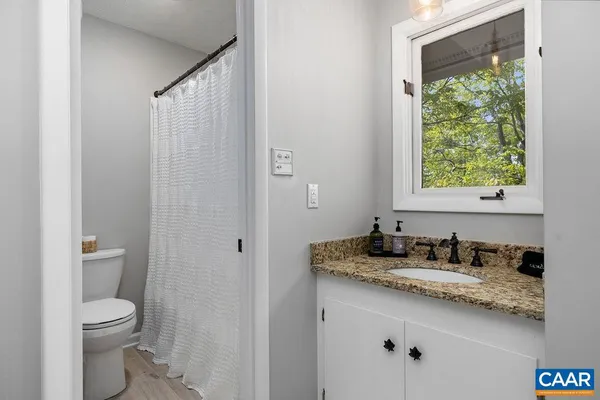 a bathroom with a granite countertop sink toilet and mirror