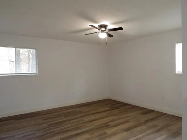 a view of empty room with wooden floor and fan