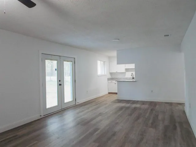 a view of kitchen and empty room with wooden floor