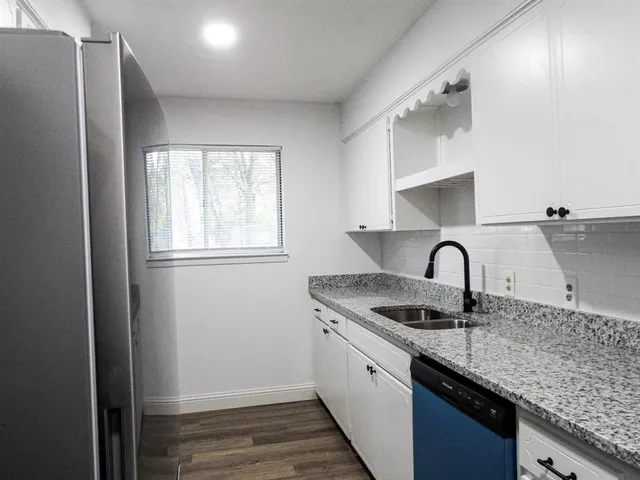 a kitchen with granite countertop a sink stainless steel appliances cabinets and a window
