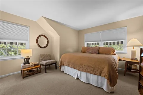 a spacious bedroom with a bed a window and a lamp on table