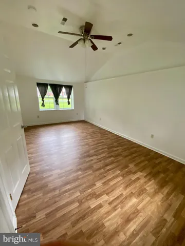 an empty room with wooden floor and ceiling fan