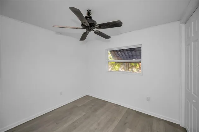 an empty room with a window and a ceiling fan
