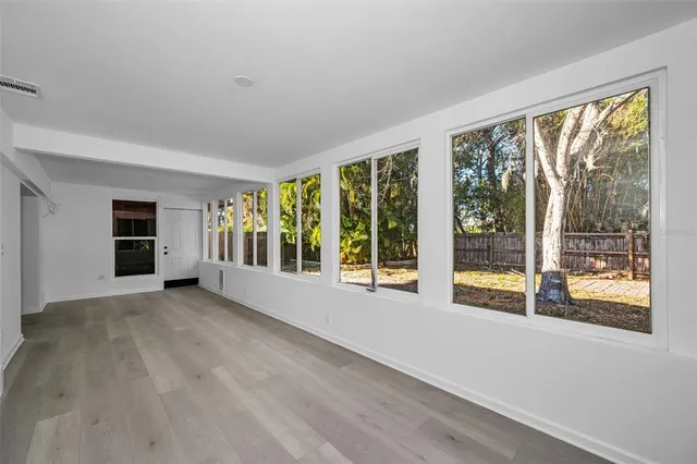 a view of an empty room with a window and kitchen view