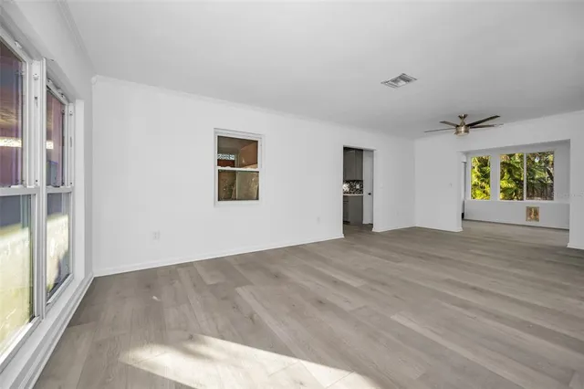 a view of an empty room with wooden floor and a window