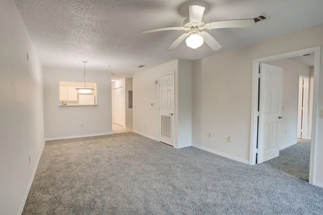 an empty room with chandelier fan and windows