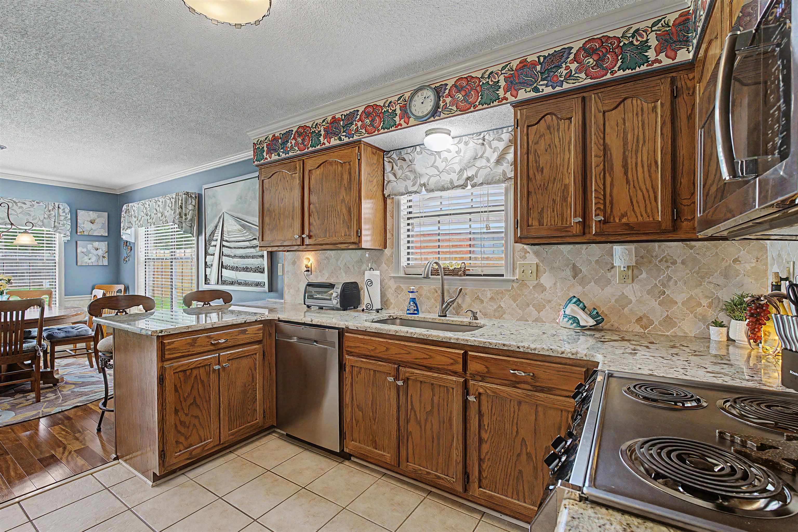 5127 Overview Ridge Memphis, TN 38141 - Photo 13 of 36 Kitchen featuring wood cabinetry, light-toned granite countertops, and a full tile backsplash
