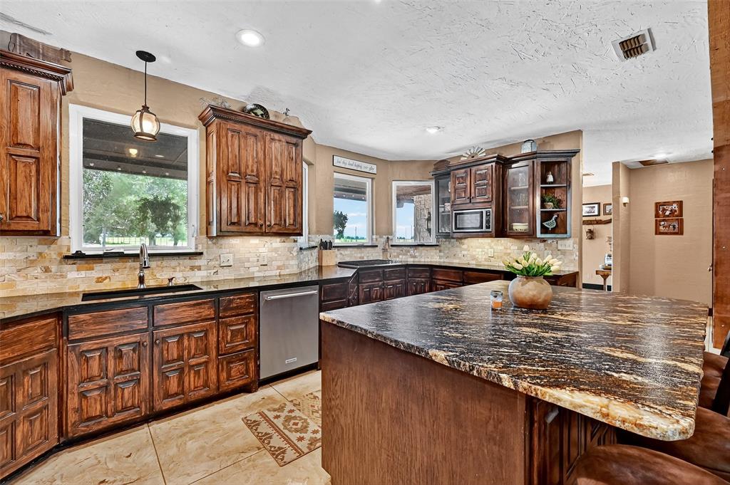1717 1/2 Batey Road Collinsville, TX 76233 - Photo 13 of 40 a large kitchen with granite countertop a sink window and cabinets