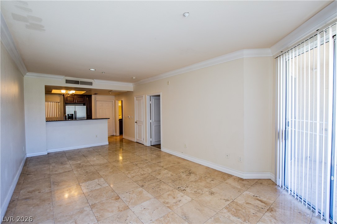230 East Flamingo Road, Unit 122 Las Vegas, NV 89169 - Photo 5 of 7 The open-concept living area flows seamlessly into the kitchen, illuminated by recessed lighting and a sliding glass door.