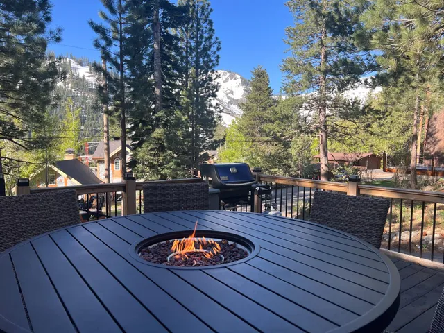 a view of a roof deck with table and chairs couches with wooden floor and fence