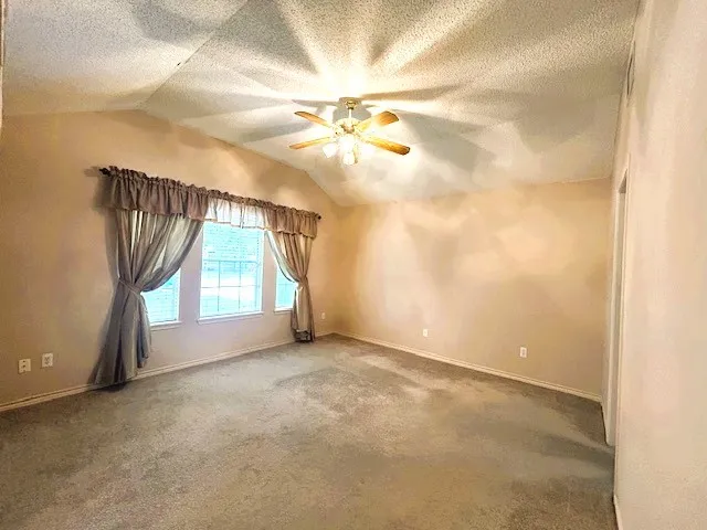 an empty room with windows and chandelier fan