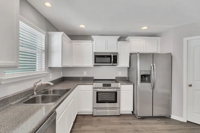 a view of an empty room with wooden floor and a ceiling fan