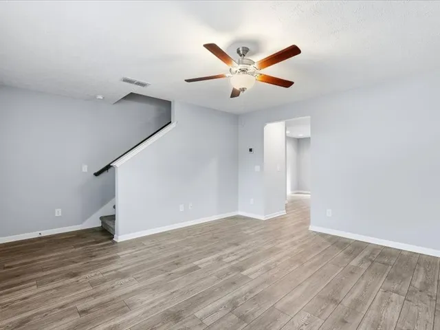 a kitchen with granite countertop a refrigerator oven a sink dishwasher and white cabinets with wooden floor