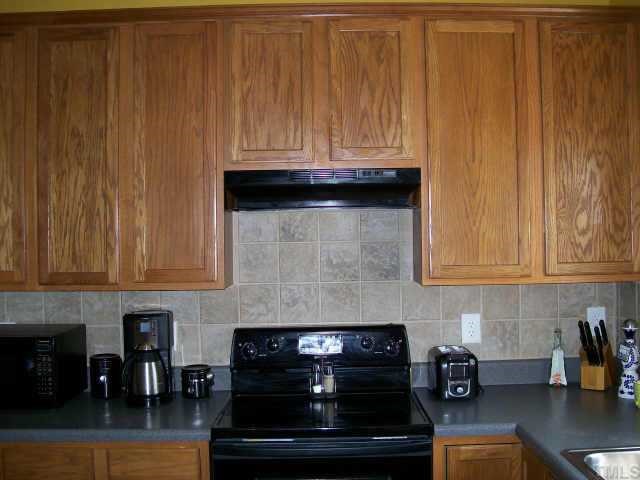 3404 Sosa Road Raleigh, NC 27610 - Photo 5 of 10 a kitchen with granite countertop white cabinets and black appliances
