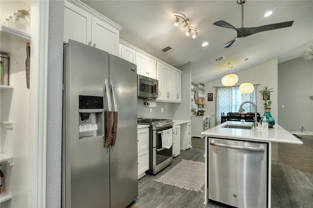 a kitchen with a sink stainless steel appliances and chandelier
