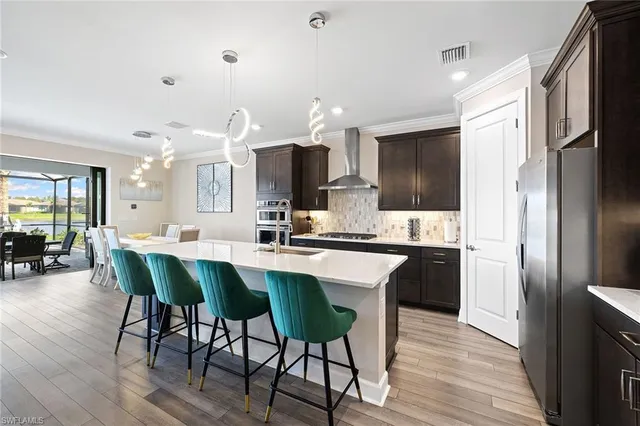 a kitchen with stainless steel appliances a dining table chairs refrigerator microwave and stove