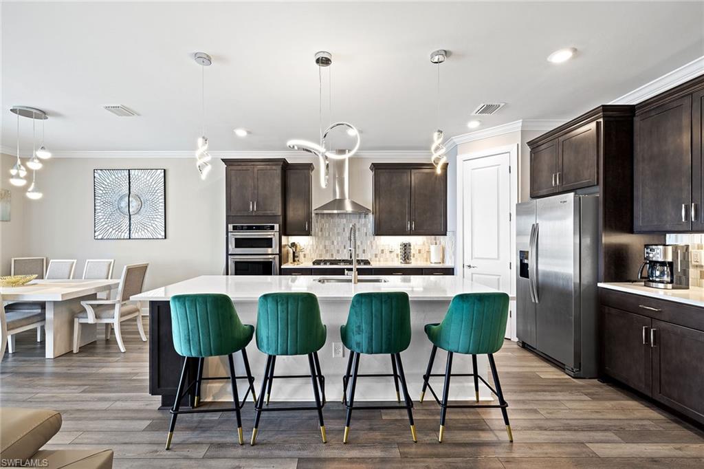 1973 Yellowfin Circle Naples, FL 34114 - Photo 19 of 44 a kitchen with stainless steel appliances a dining table chairs refrigerator and sink