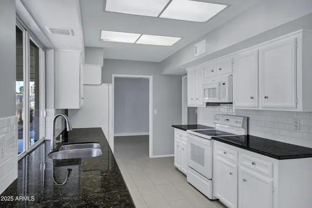 a kitchen with granite countertop a sink stove and cabinets