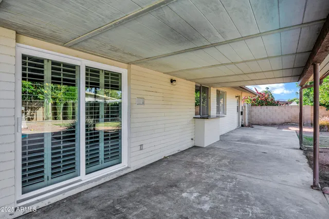 a view of a backyard with floor to ceiling window and tree