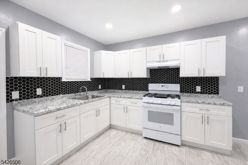 411 South 16th Street, Unit 1 Newark, NJ 07103 - Photo 5 of 39 a kitchen with a sink dishwasher a stove and white cabinets
