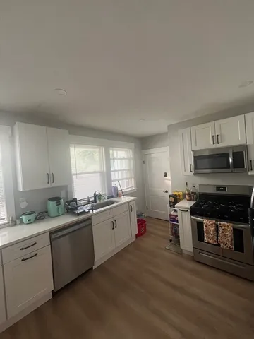 a kitchen with appliances a sink cabinets and a window