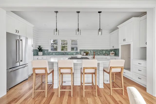 a kitchen with stainless steel appliances granite countertop a refrigerator a stove and white cabinets with wooden floor