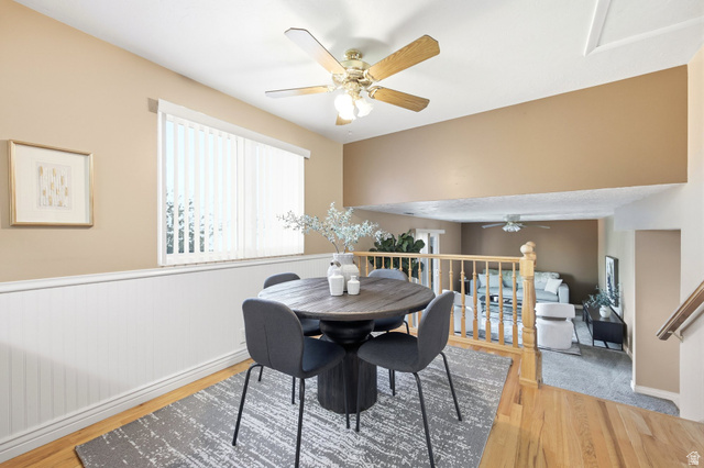 734 Sandy Dunes Drive Sandy, UT 84094 - Photo 7 of 36 Dining area featuring wood-finish flooring, a white wainscoting accent wall, and a ceiling fan