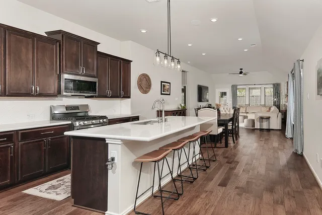 a kitchen with stainless steel appliances granite countertop a stove top oven a sink dishwasher and a microwave oven with wooden floor