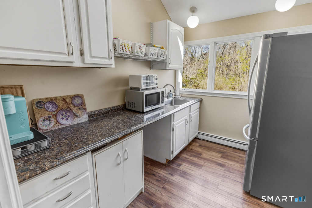 49 River Street Old Saybrook, CT 06475 - Photo 24 of 28 a kitchen with stainless steel appliances granite countertop a sink a stove a microwave and wooden cabinets