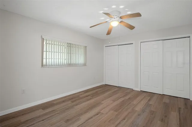 an empty room with wooden floor ceiling fan and window