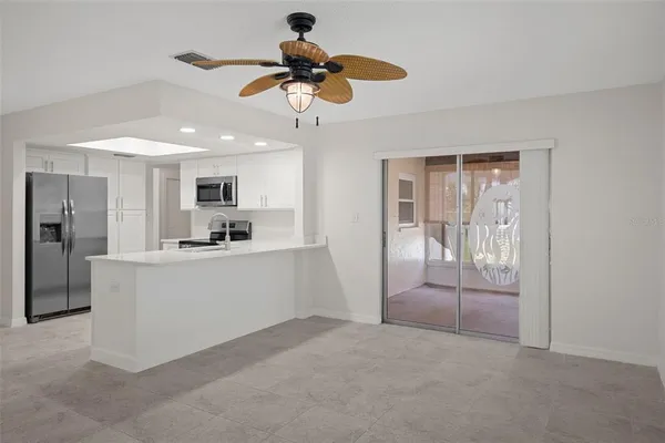 an empty room with wooden floor chandelier fan and windows
