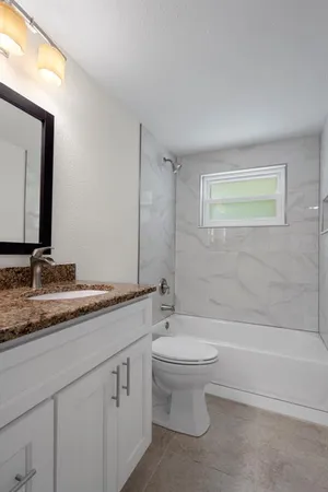 a bathroom with a granite countertop sink a toilet and a bathtub