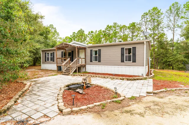 a front view of house with yard outdoor seating and covered with trees