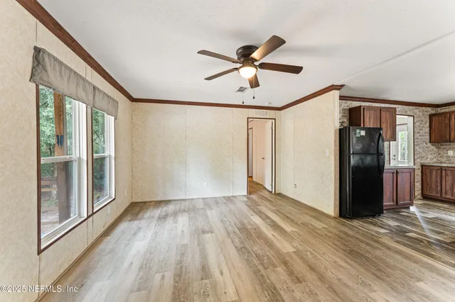 a view of empty room with wooden floor and fan