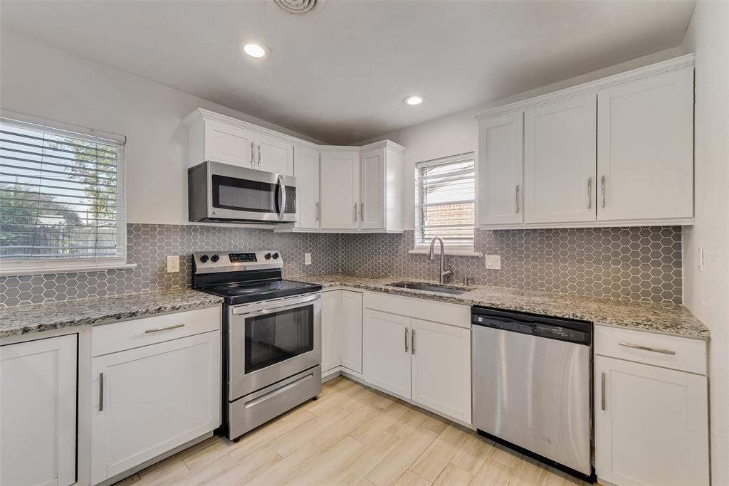 413 Simmons Drive Hurst, TX 76053 - Photo 21 of 26 a kitchen with granite countertop white cabinets and appliances